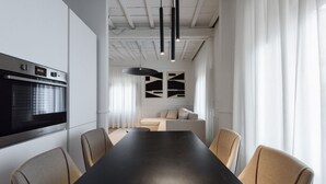 Una cocina moderna con horno integrado, una mesa de comedor con sillas y un sofá al fondo.