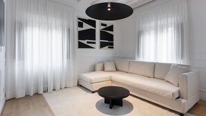 Una sala de estar moderna con un sofá seccional color beige, una mesa de centro negra redonda y un cuadro abstracto grande en la pared.