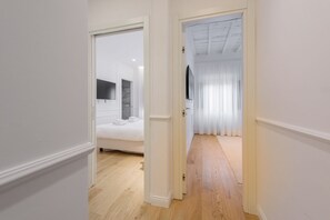 A hallway leading to a bedroom with a bed, a mirror, and a window with curtains. - Pitti Prestige in Florence by Mmega (Firenze)