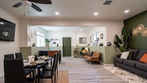 A modern living room with a sofa, a dining area with a table and chairs, and a kitchen in the background. - Tranquil Haven: Luxurious and Spacious Guest Suite
 (Colorado Springs)