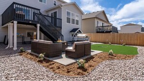 A two-story house with a covered patio, outdoor furniture, and a fenced backyard. - Tranquil Haven: Luxurious and Spacious Guest Suite
 (Colorado Springs)