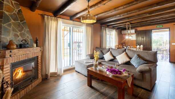 A cozy living room with a fireplace, a sofa, and a coffee table with flowers.