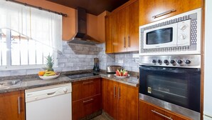 A kitchen with wooden cabinets, a built-in microwave, a stove, and a dishwasher.
