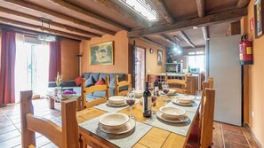 A dining area with wooden furniture, a table set for four, and a kitchen in the background. - Casa La Bimbre Algatocín by Ruralidays (Málaga)