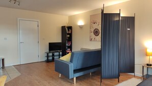 Ein modernes Wohnzimmer mit einer Couch, einem Bücherregal und einem Fernseher.