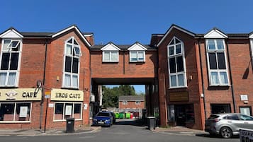 A two-story building with a large arched entrance, a cafe on the ground floor, and a sign for a business on the second floor.