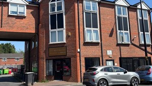 A two-story brick building with large windows and a sign for 'Rich Interiors & Fabrics'.