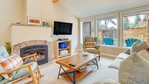 A living room with a fireplace, a television, and a view of the outdoors. - Near Eats & Brews! Beautiful Seattle Home w/ Patio (Seattle)