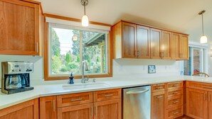 A modern kitchen with wooden cabinets, a stainless steel dishwasher, and a coffee maker. - Near Eats & Brews! Beautiful Seattle Home w/ Patio (Seattle)
