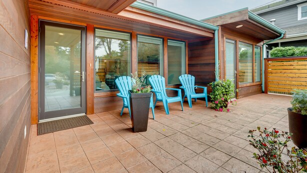 A patio with wooden flooring, a sliding glass door, and blue Adirondack chairs. - Near Eats & Brews! Beautiful Seattle Home w/ Patio (Seattle)