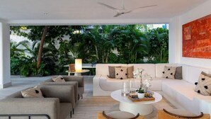 Ein modernes Wohnzimmer mit einer weißen Sofagarnitur, einem runden Couchtisch und Korbstühlen.