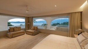 Ein geräumiges Schlafzimmer mit einem großen Bett, zwei Sofas und Meerblick.