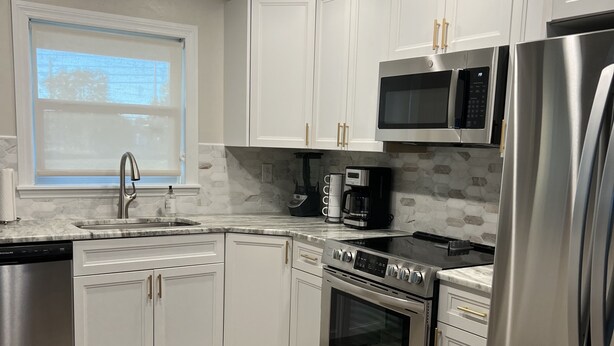 A modern kitchen with white cabinets, stainless steel appliances, a microwave, and a refrigerator.