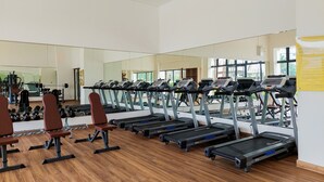 Un gimnasio con cintas de correr, mancuernas y bancos.