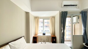 A hotel room with a bed, a desk, a chair, and a window with curtains. - Great Choice Studio Apartment LRT City Jatibening (Bekasi)