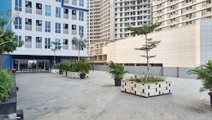 A modern building with multiple floors, outdoor seating area, and potted plants. - Homey And Relaxing Studio Grand Dhika City Apartment (Bekasi)