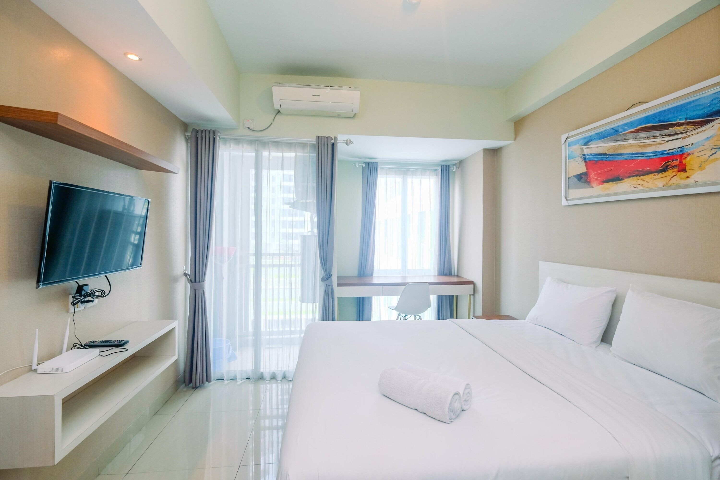 Une chambre d’hôtel avec un lit, une télévision, un bureau et un tableau au mur.