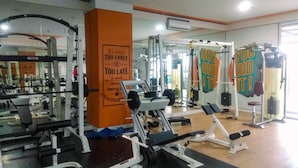 A gym with various exercise equipment, including a bench press, squat rack, and weight benches. - Fabulous Studio Grand Dhika City Apartment (Bekasi)