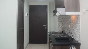 A compact kitchen with a dark door, a small sink, and a microwave.