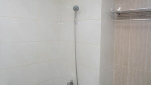 A shower with a handheld showerhead and a wall-mounted faucet.