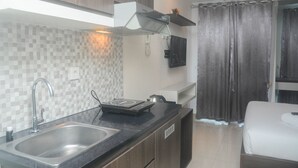 A modern kitchen with a built-in sink, a microwave, and a coffee maker. There is a window with curtains and a small shelf above the sink.