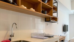 A modern kitchen with a stainless steel sink, wooden cabinets, and a white tiled backsplash. - Best Deal Studio Tokyo Riverside Pik 2 Apartment (Teluknaga)