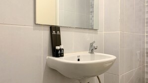 A white bathroom sink with a chrome faucet, a mirror above it, and a towel rack with two towels. - Best Deal Studio Tokyo Riverside Pik 2 Apartment (Teluknaga)