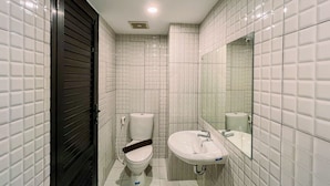Un baño pequeño y moderno con azulejos blancos, un inodoro, un lavabo y un espejo.