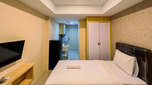 Habitación de hotel con cama, televisor en un mueble bajo, escritorio con silla y armario.