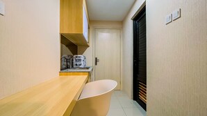 Una cocina estrecha con mostrador de madera, una silla blanca y una puerta que da a una habitación oscura.