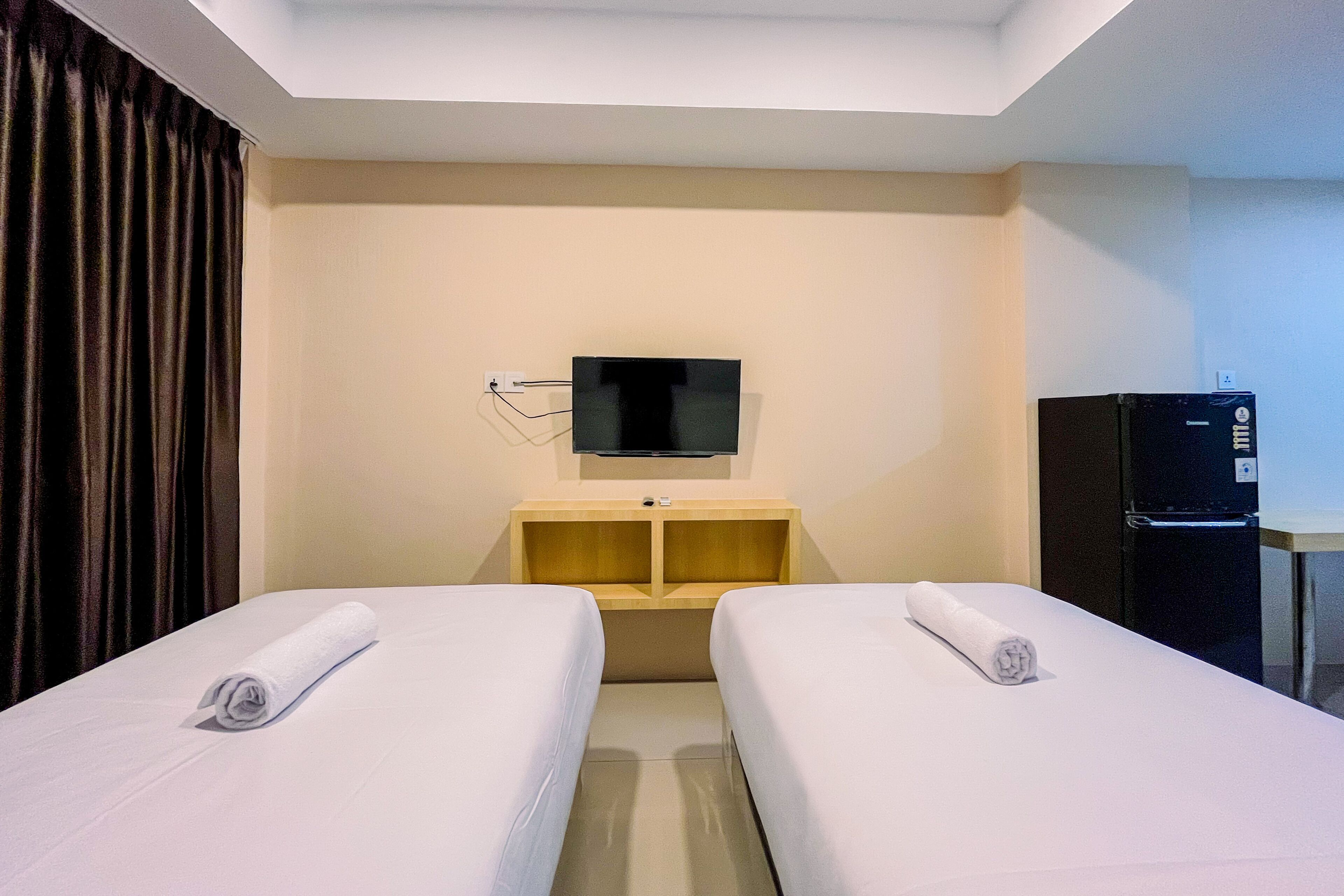 Ett hotellrum med två sängar, en TV, en minibar och ett skrivbord.