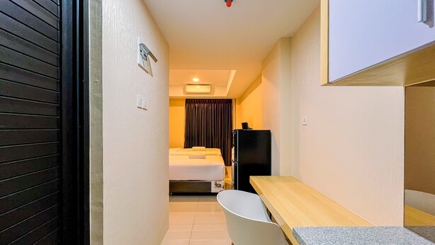 Habitació d'hotel senzilla amb llit, escriptori, cadira, nevera i un petit rentapenes.
