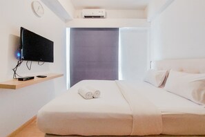 Relax in a serene space with a neatly made bed, flat-screen TV, and air conditioning.