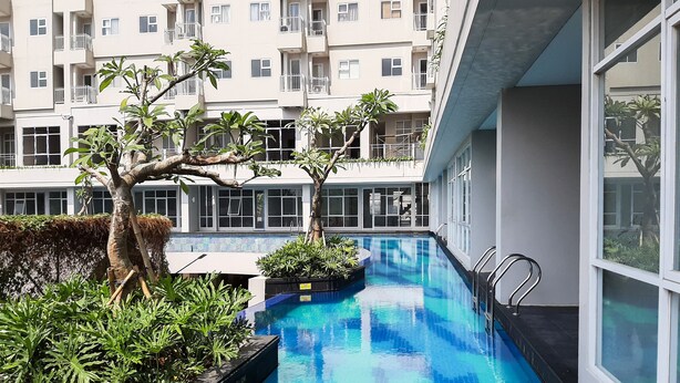 A swimming pool with a 120 cm depth, surrounded by greenery and modern buildings. - Homey Studio At Bintaro Icon Apartment (South Tangerang)