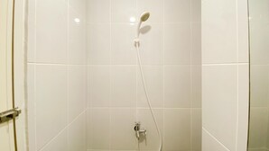 Een douche met een handdouche en een bedieningskraan aan de muur.