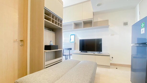 Quarto de hotel moderno com cama, televisão, frigorífico e estantes embutidas.
