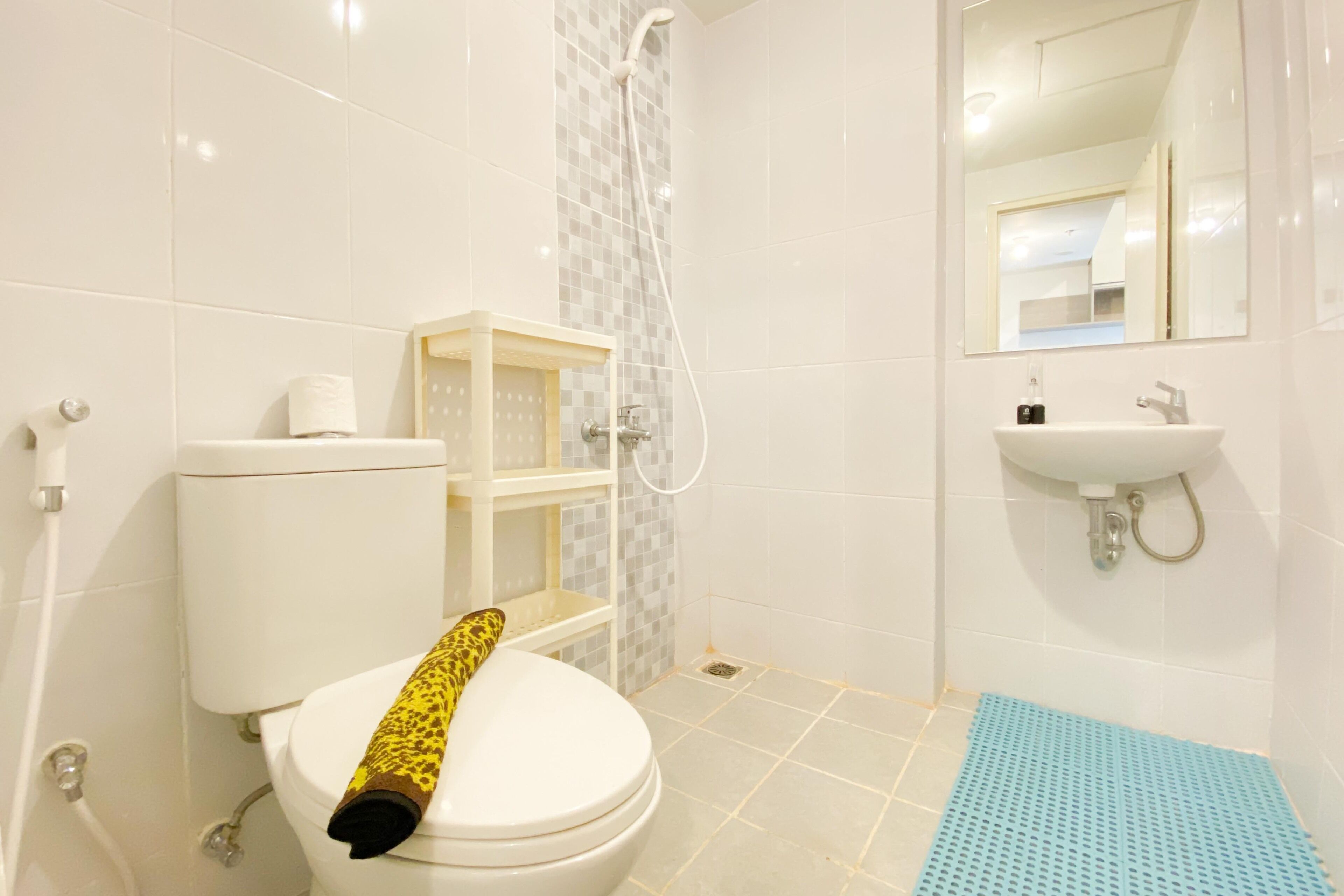 A bathroom with a toilet, shower, sink, and a mirror.