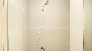 A shower with a handheld showerhead and a wall-mounted faucet. - Cozy Studio Tokyo Rivervide Pik 2 Apartment (Teluknaga)