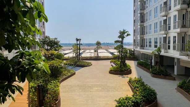 A rooftop garden with pathways, planters, and a view of distant buildings. - Cozy Studio Tokyo Rivervide Pik 2 Apartment (Teluknaga)