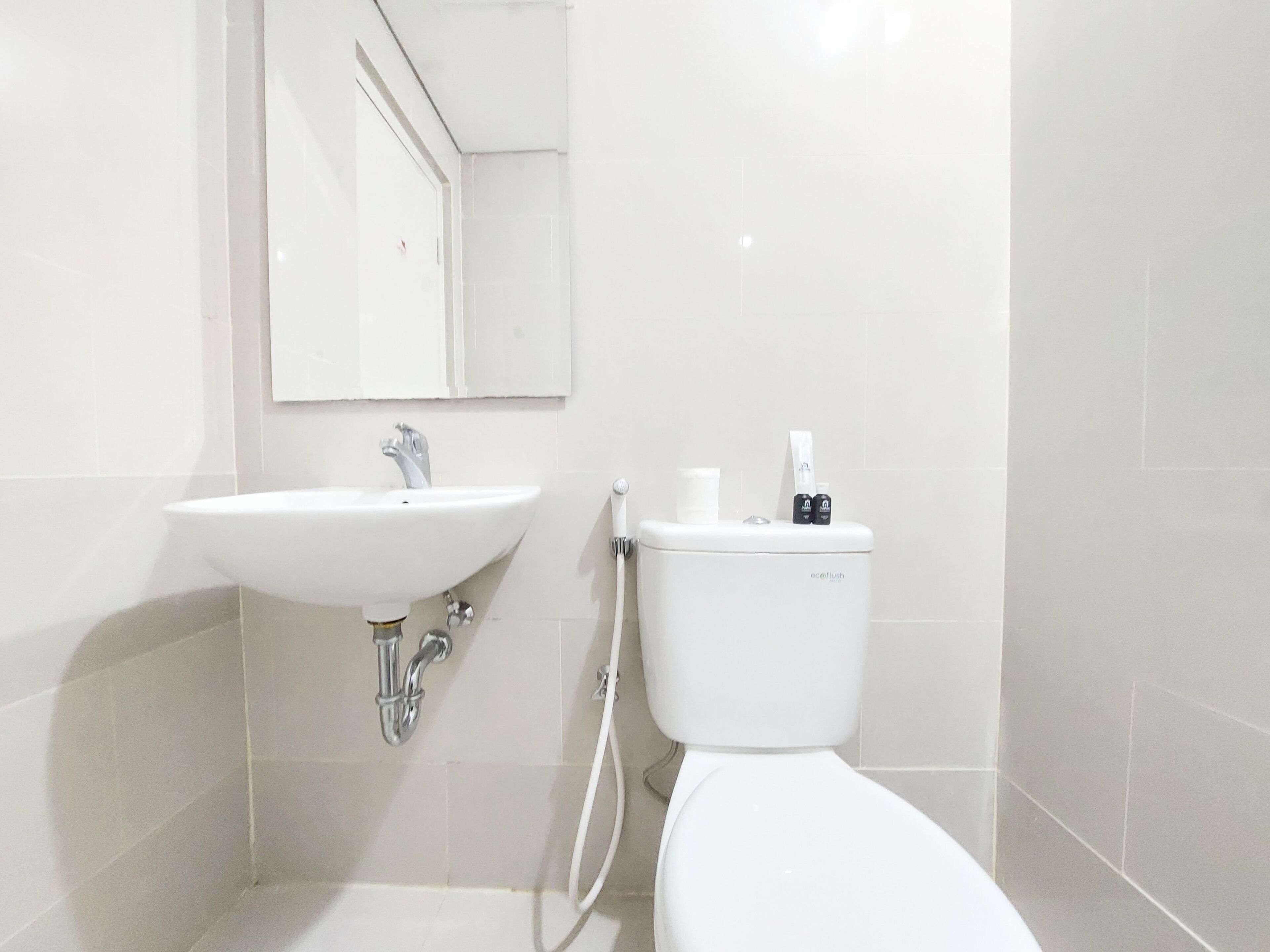 A bathroom with a white sink, a mirror, and a toilet.