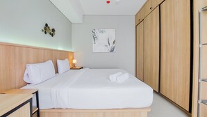 Ein modernes Hotelzimmer mit einem hölzernen Kopfteil, einem ordentlich bezogenen Bett mit weißer Bettwäsche, einem Nachttisch mit Lampe, einem an der Wand hängenden abstrakten Kunstwerk und einem Schrank mit Schiebetüren.