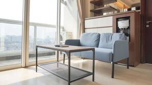 A modern living room with a sofa, a coffee table, and a built-in espresso machine.