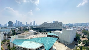 A modern building with a unique curved roof, surrounded by other structures and a city skyline in the background.