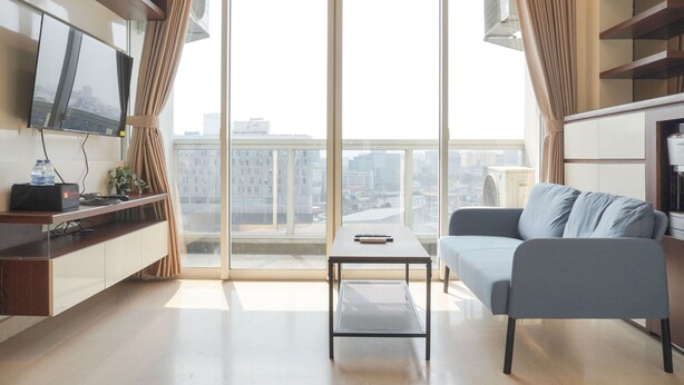 A modern living room with a sofa, a coffee table, and a TV mounted on the wall.