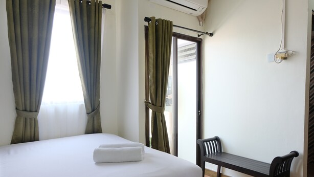 A hotel room with a bed, a bench, and a window with curtains. - Spacious And Modern 3Br Apartment At Gateway Ahmad Yani Cicadas (Bandung)