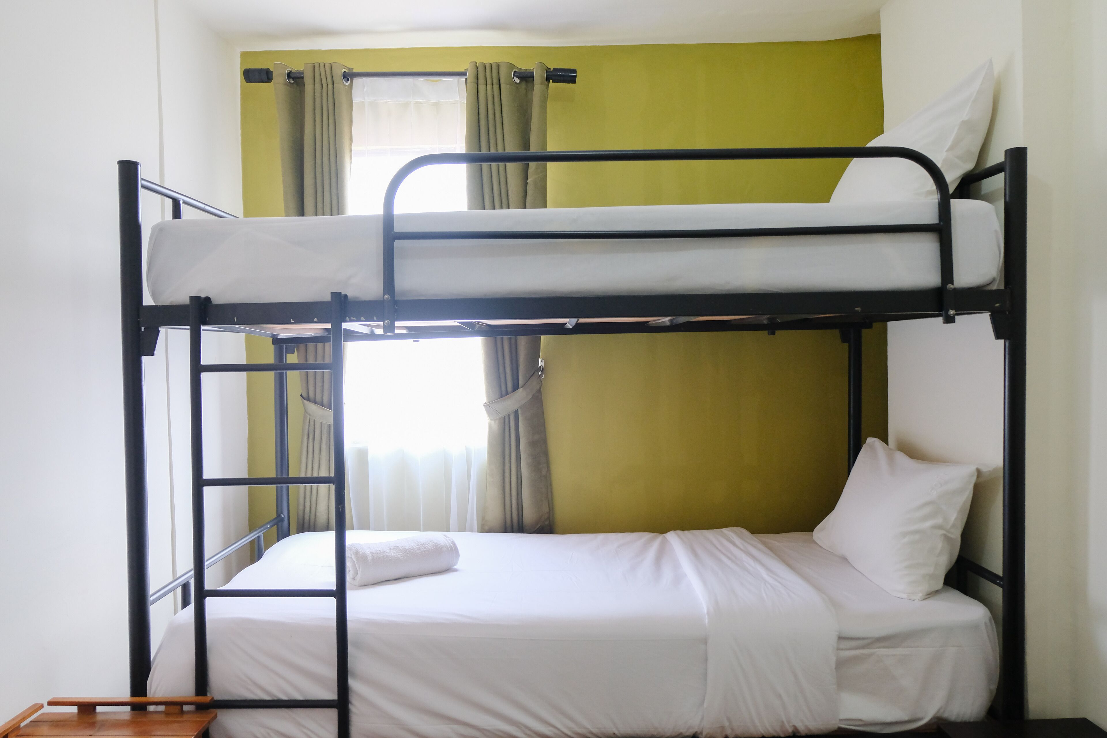 A bunk bed with white bedding and a wooden side table.