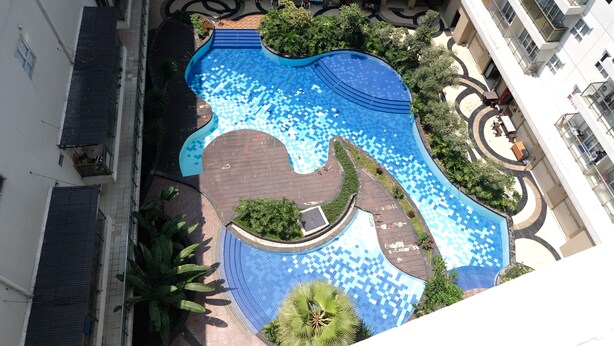 Une vue aérienne d’une piscine entourée de verdure et de sentiers.