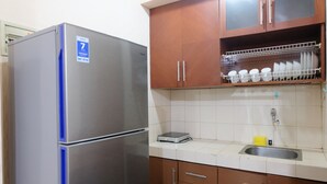 A kitchen with a stainless steel refrigerator, a sink, and wooden cabinets.