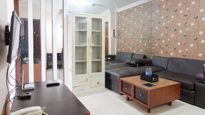 A living room with a dark brown sofa, a wooden coffee table, a glass cabinet, and a patterned wall.