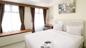 A hotel room with a large bed, a desk, and a painting on the wall. - Homey And Cozy Stay Studio Room Pollux Chadstone Apartment (Cikarang)